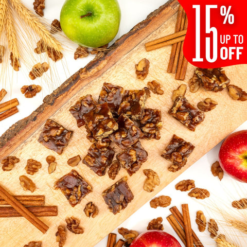 Squares of Apple Pie Walnut Chella FruityNuts Bites on a wooden board with apples, cinnamon, wheat stalks, and a “15% off” label in the corner. Rustic and appetizing.