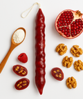 Churchkhela, pomegranate, walnuts, raspberries, and a wooden spoon with flour a white background