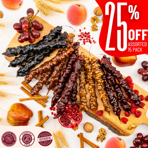 15 assorted churchkhelas are arranged on a wooden board with apricots, raspberries, grapes, and pomegranates. A red text overlay offers 25% off a 15-pack.