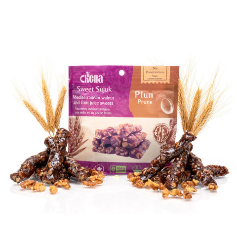 Package of Chella FruityNuts Bar plum and walnut flavour surrounded by clusters of shiny bars and wheat stalks on a white background.