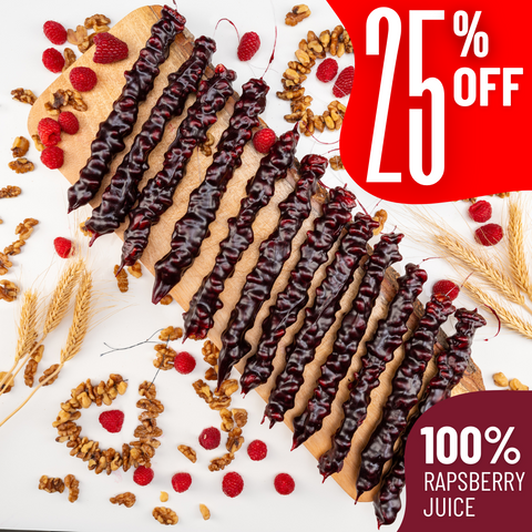 Assortment of 12 raspberry churchkhela on a wooden board, surrounded by walnuts, raspberries, and wheat on a white background. Red tags display "25% off' and "100% Raspberry Juice"