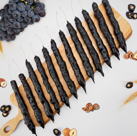 Grape Hazelnut Chella Churchkhela on wooden board with grapes and hazelnuts, showcasing natural ingredients of this healthy treat.