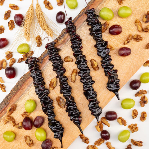 Grape Walnut Chella Churchkhela with vibrant grapes and walnuts on a wooden board, offering a healthy snack choice.