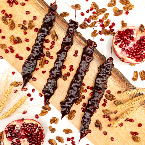 Pomegranate Walnut Chella Churchkhela with pomegranate seeds and walnuts displayed on a rustic board